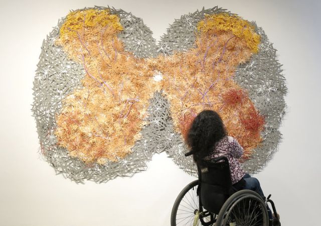 This is a picture of a person in a wheel chair looking at a piece of art