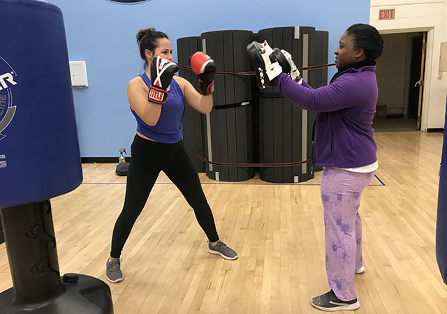 Instructor sparring with a student in boxing class