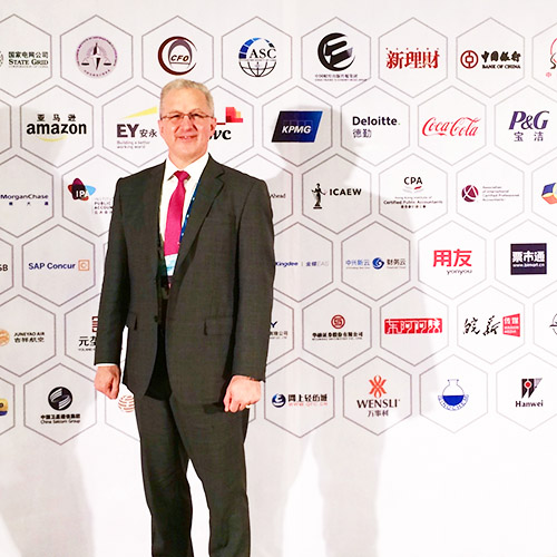 USD alumnus and CFO of Technical Rubber Company, William Dopp '00, poses in front of a backdrop of international company logos at a conference