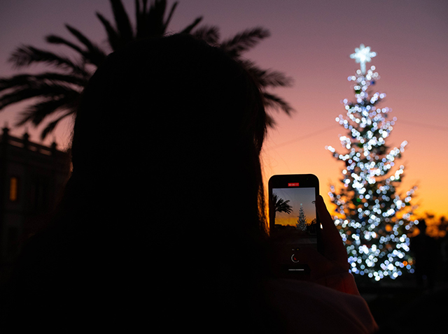 A USD student records a short video of the Christmas tree lighting