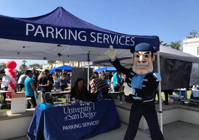 Diego Torero pointing to USD Parking Services sign-up tent